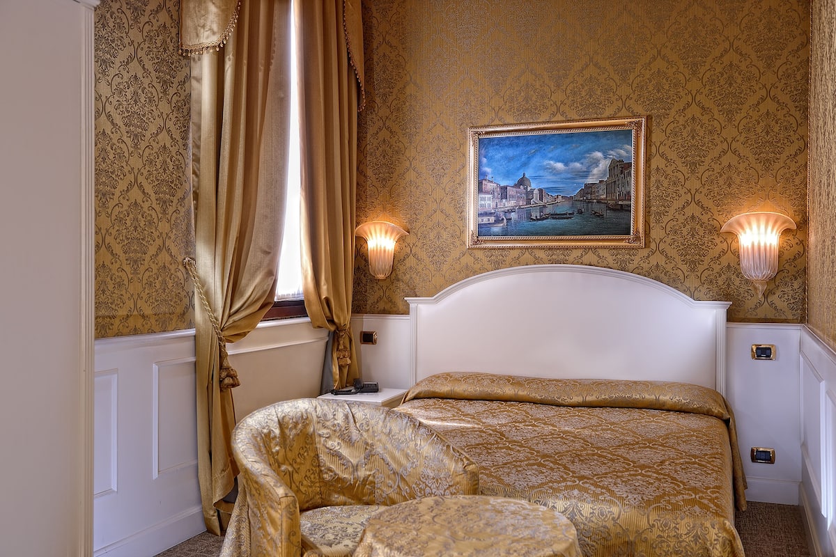 Ein Hotelzimmer mit einem Bett, einem Bild an der Wand und zwei Wandleuchten.
