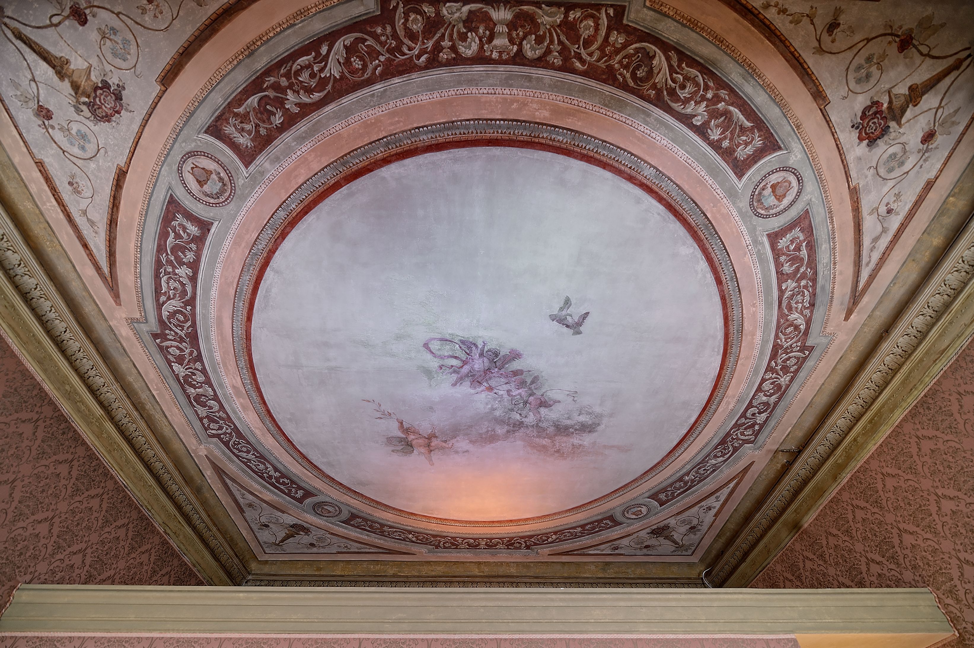 A ceiling with a circular fresco and ornate moldings.