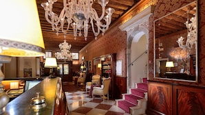 A lobby with a checkered floor, a bar area with a minibar, and a staircase leading to another level.
