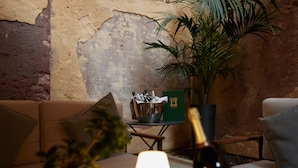 A cozy living area with a sofa, a table with a bottle, and a potted plant.
