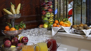 A breakfast table with fruits, a fruit basket, and two pitchers of juice.