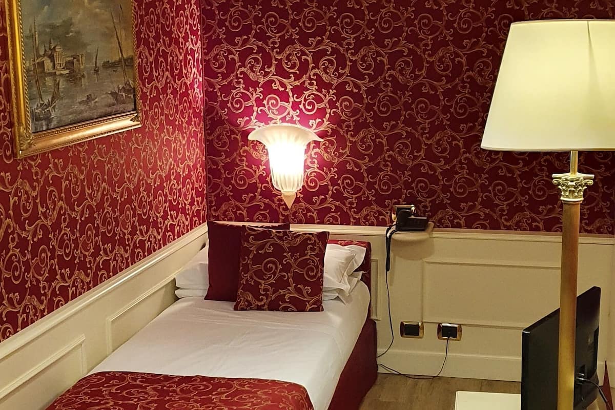 Ein Hotelzimmer mit Bett, Schreibtisch, Stuhl, Lampe und einem Bild an der Wand.