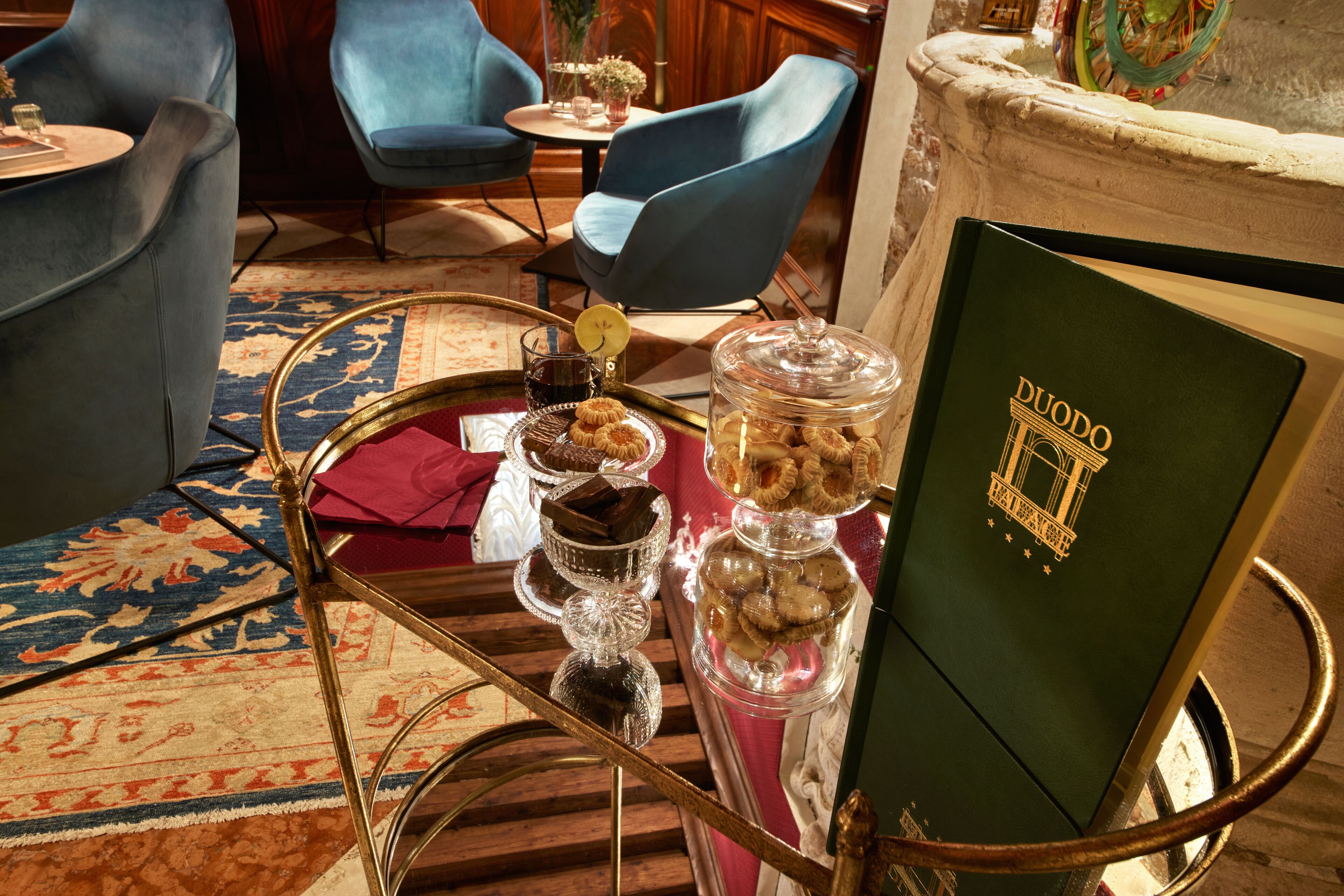 A room with a green sign, a glass jar with cookies, a tray with pastries, and blue chairs.