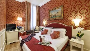 A hotel room with a large bed, two bedside tables, a TV, and a painting on the wall.