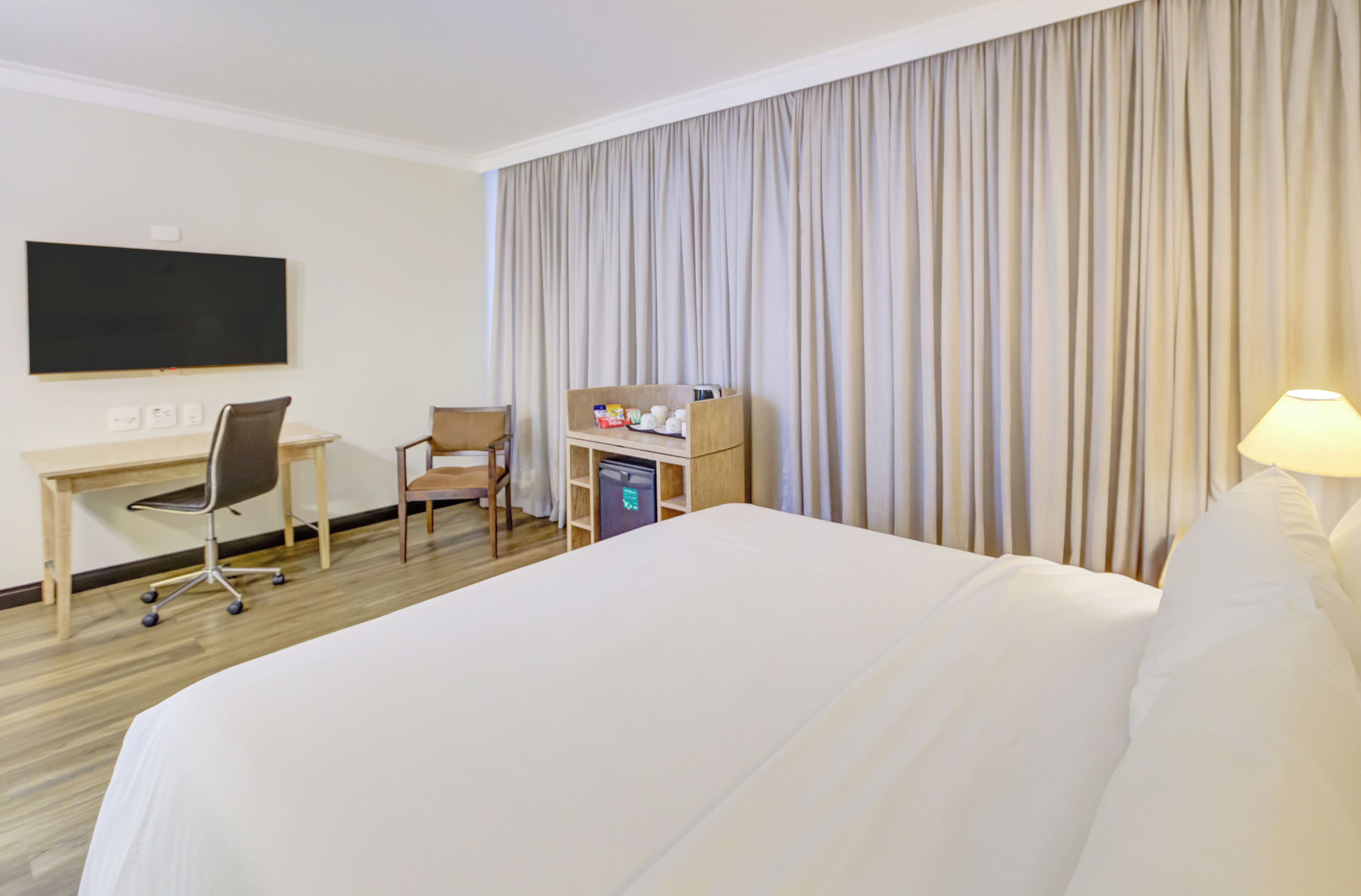 Une chambre d’hôtel équipée d’un lit, d’un bureau, d’une chaise et d’un téléviseur.