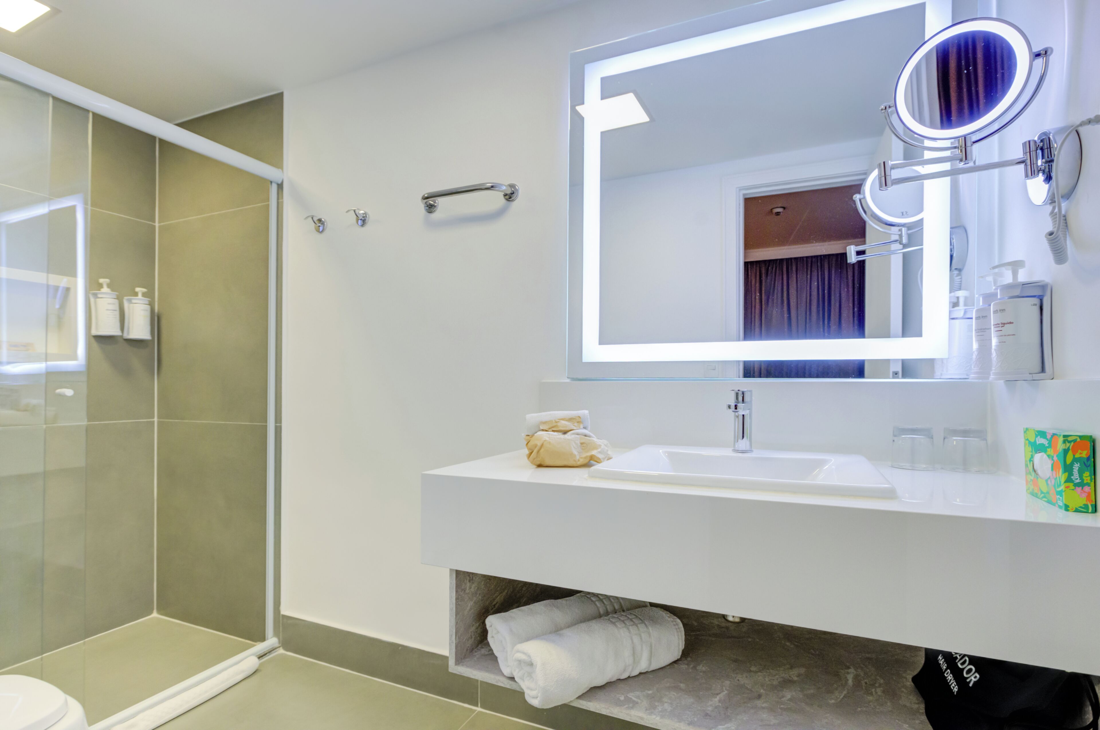A modern bathroom with a glass shower enclosure, a white sink with a mirror, and a towel rack.