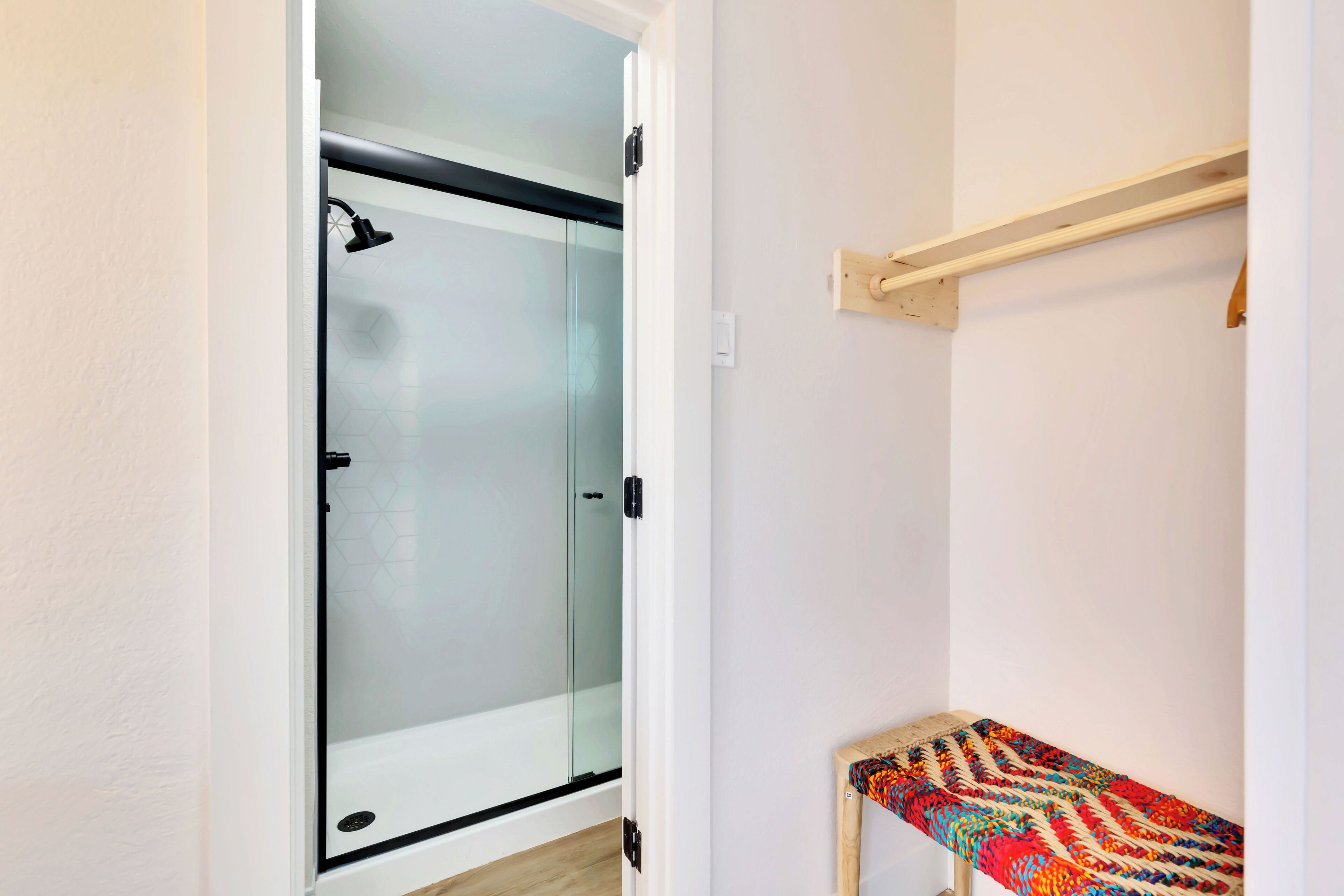 Un bagno con cabina doccia in vetro, una panca in legno e un porta asciugamani.