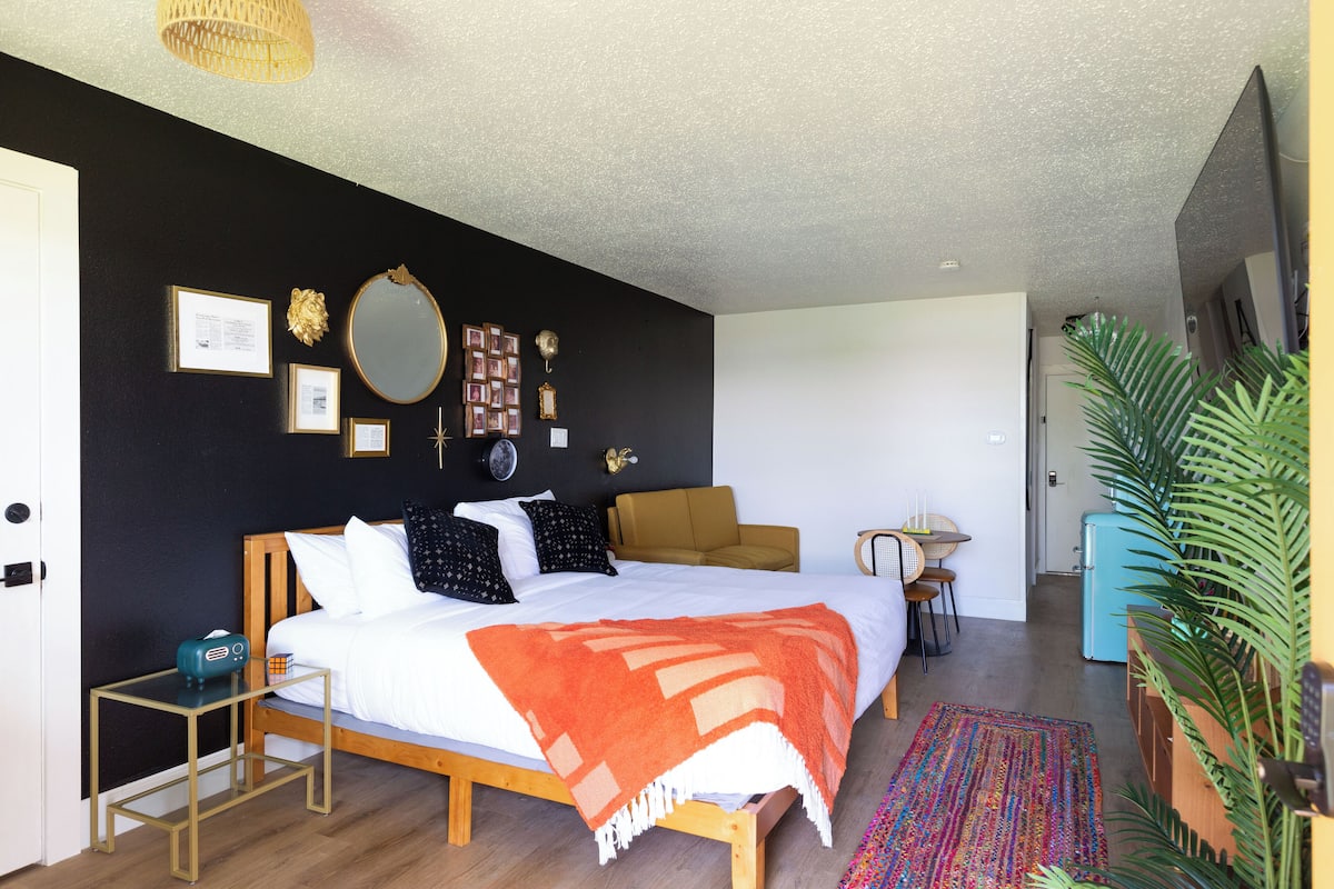 A bedroom with a bed, bedside table, and a mirror on the wall.