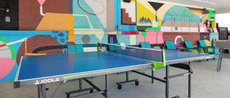 Una mesa de ping pong con un mural colorido al fondo.