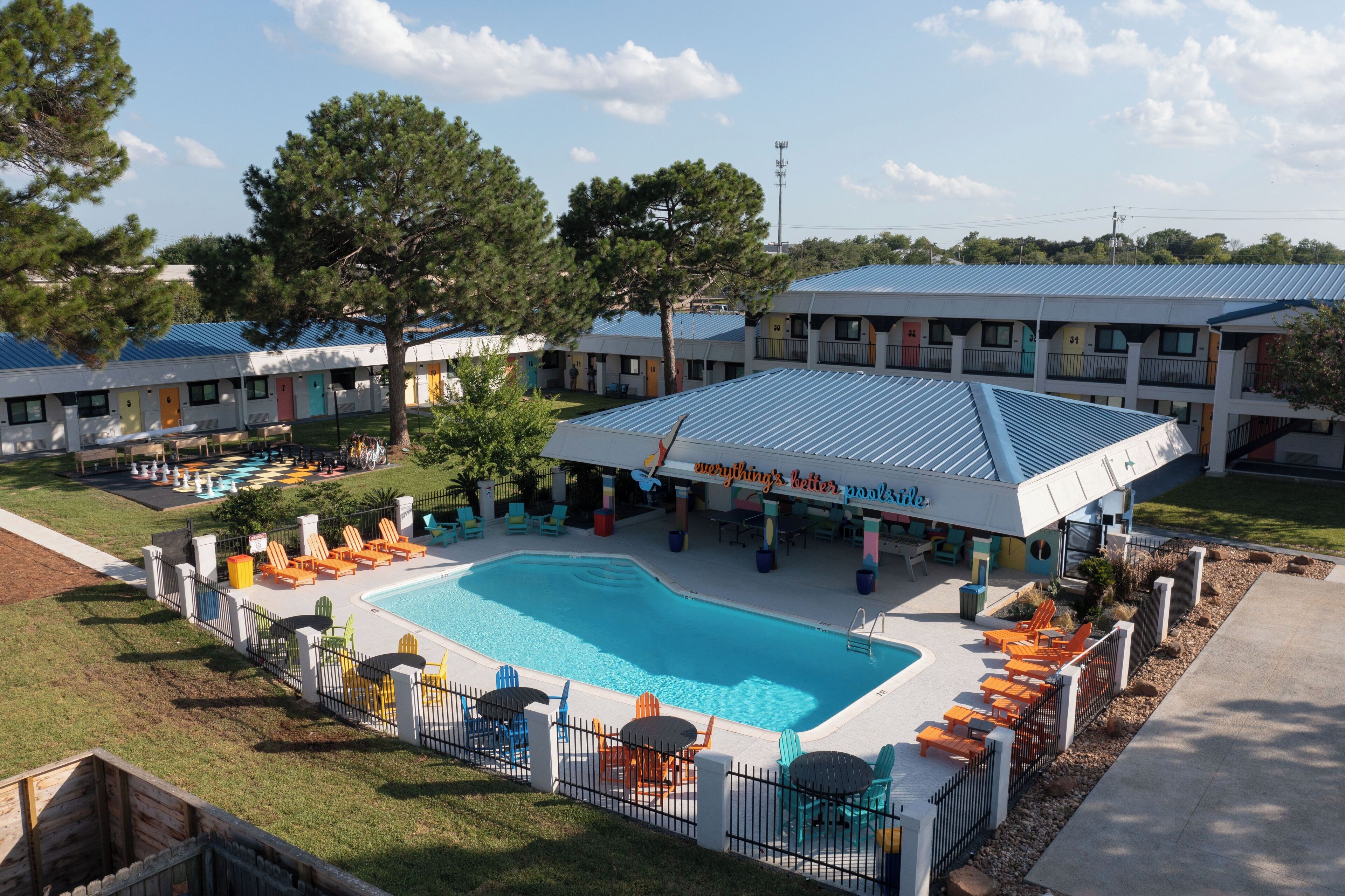Zona de piscina con sillones de descanso y un área de estar cubierta.
