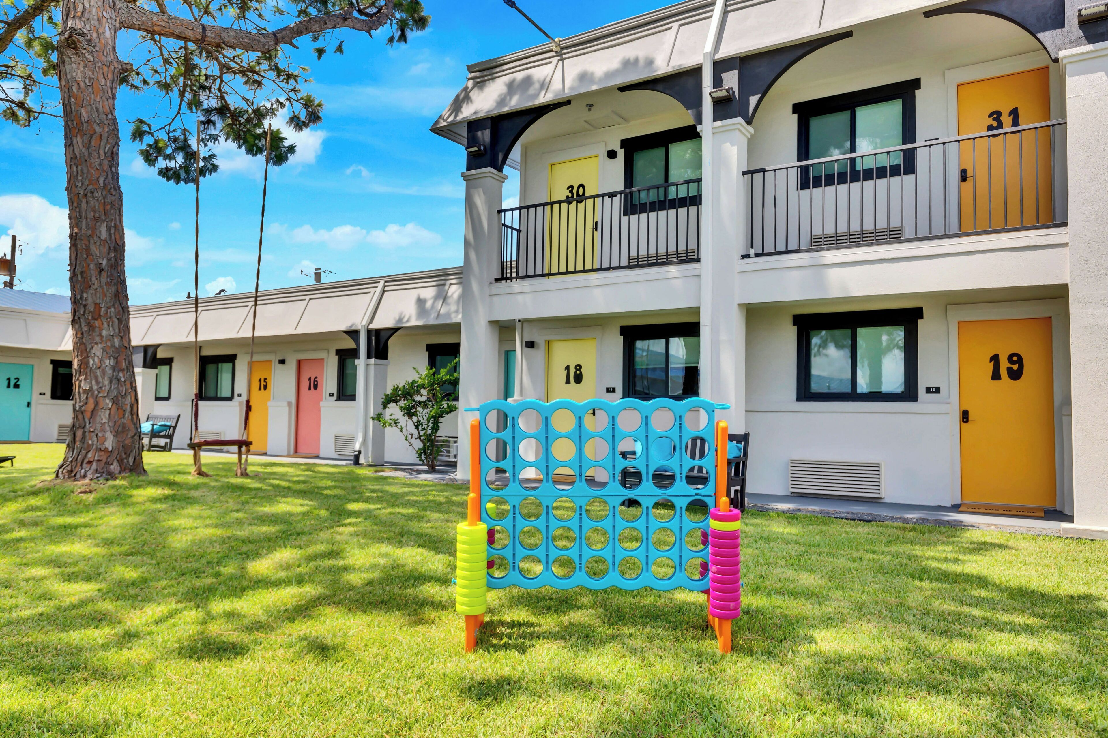 Un motel con porte numerate, un cancello blu e un albero sullo sfondo.