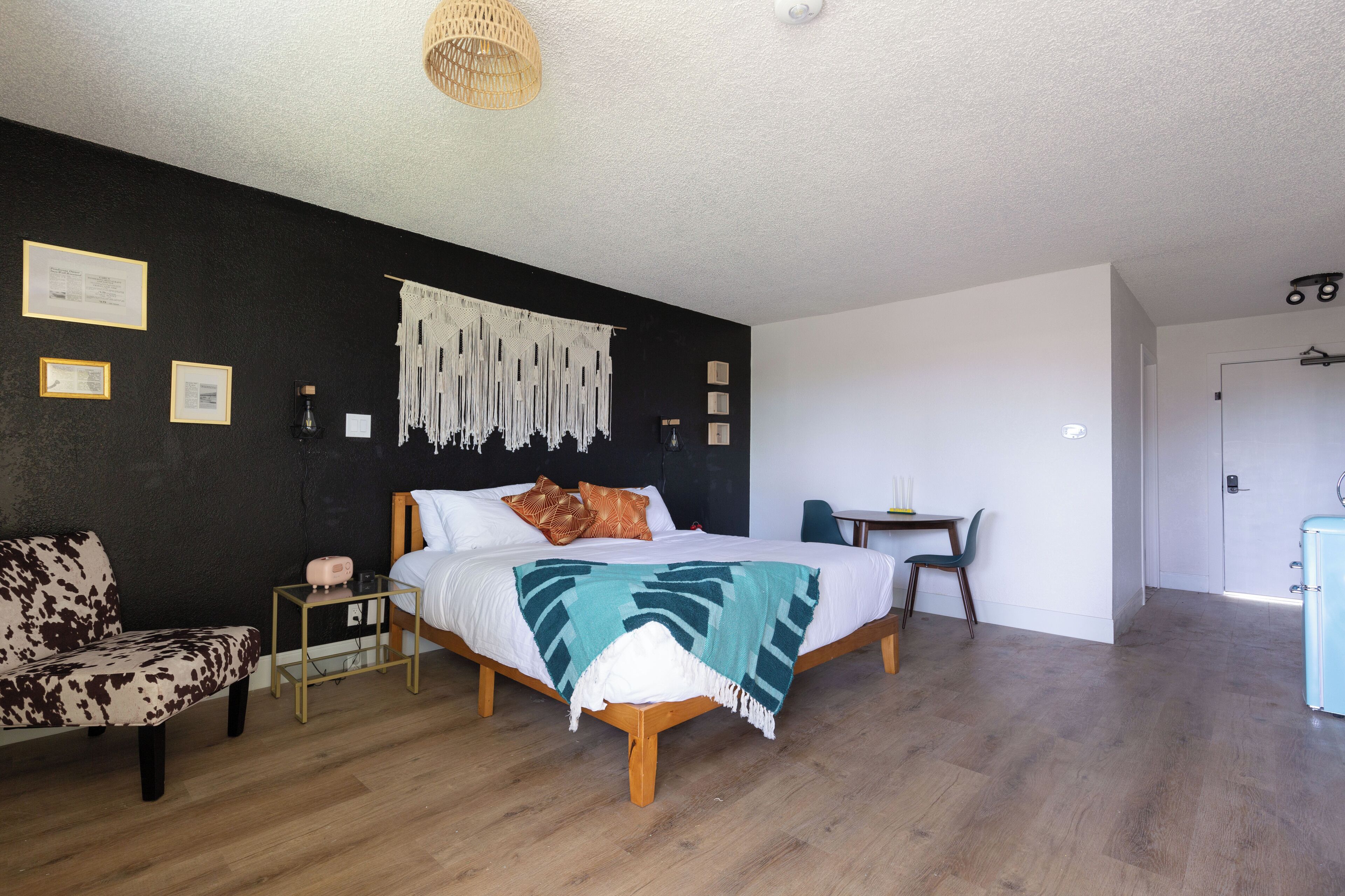 A bedroom with a bed, a chair, a small table, and a desk.
