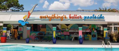 A poolside area with a colorful mural and a sign that reads "everything's better poolside."