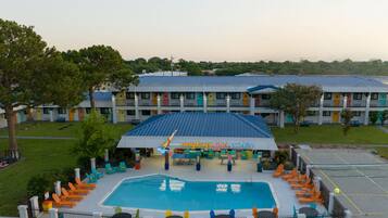 Un hotel con piscina, mobiliario exterior y una fachada colorida.