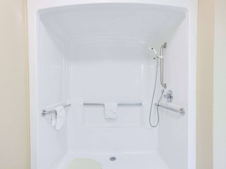 A white bathtub with a showerhead and grab bars.