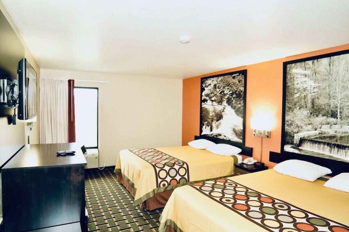 Una habitación de hotel con dos camas, un escritorio y una televisión.