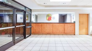 A reception area with a wooden counter, a glass door entrance, and a ceiling with recessed lighting.