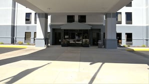 A modern building with a covered entrance, large windows, and a symmetrical facade.