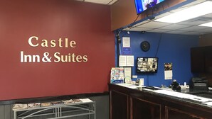 A hotel reception area with a red wall, a television mounted above the reception desk, and a sign reading "Castle Inn & Suites". - Castle Inn & Suites Anadarko (Anadarko)