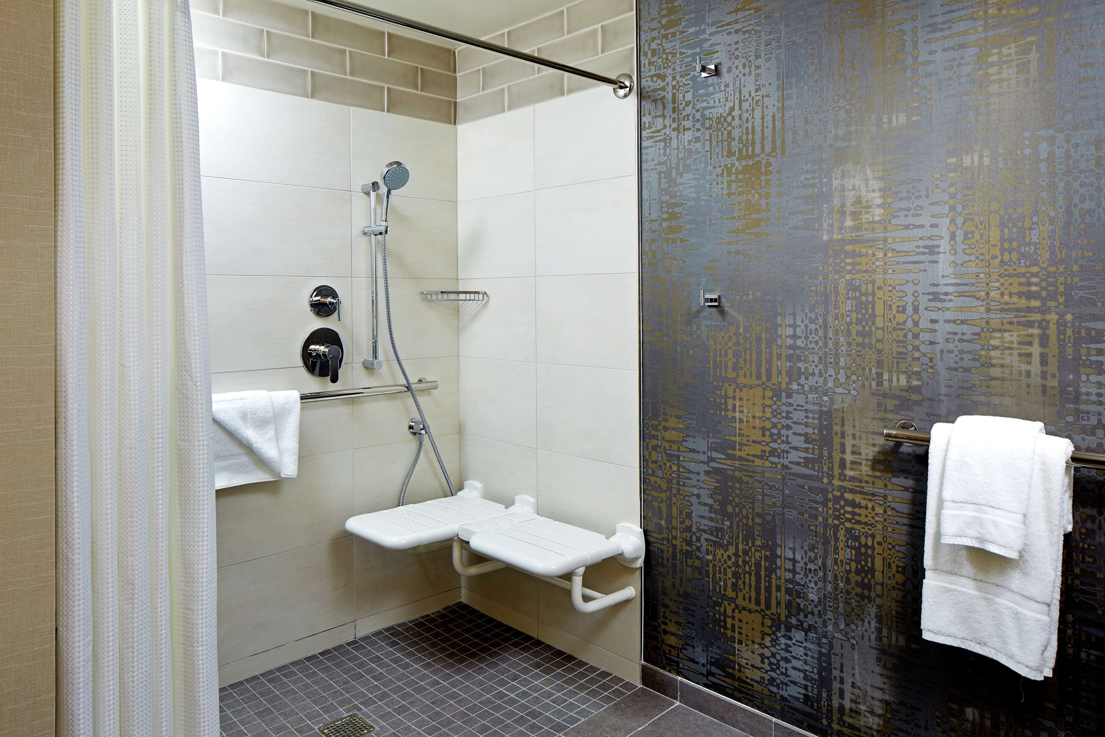 A shower area with a glass door, a white towel rack, and a showerhead.