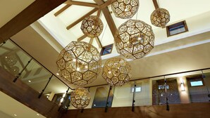 Un intérieur spacieux avec un plafond haut et de nombreuses suspensions lumineuses de forme sphérique.