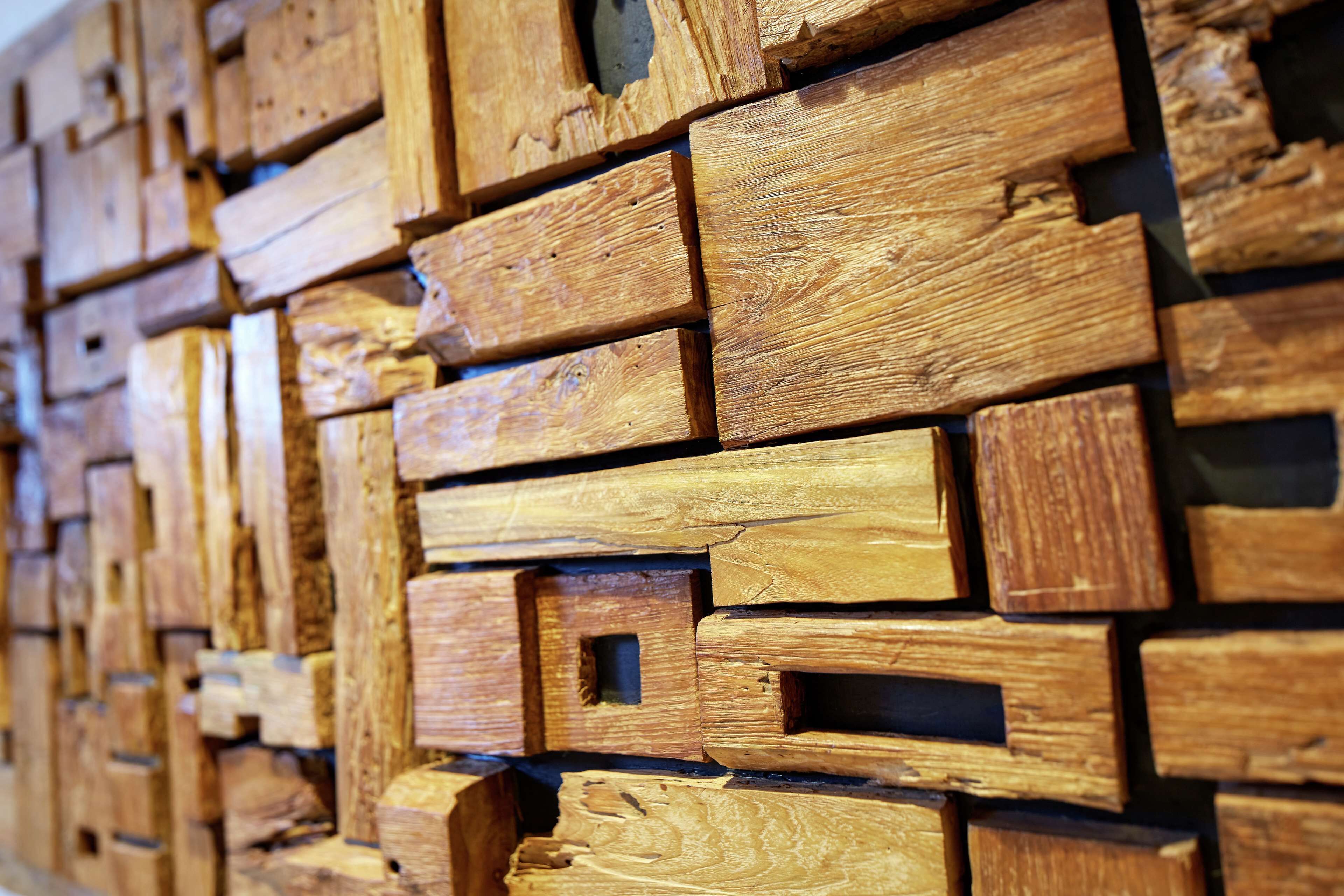 Een muur gemaakt van houten planken in verschillende formaten, gelegd in een verspringend patroon.