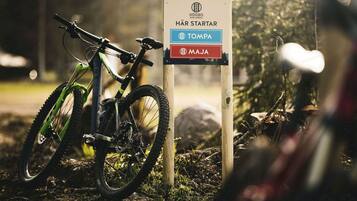Una bicicleta de montaña estacionada junto a un letrero con indicaciones a 'HÄR STARTAR' (EMPIEZA AQUÍ), 'TOMPA' y 'MAJA'.