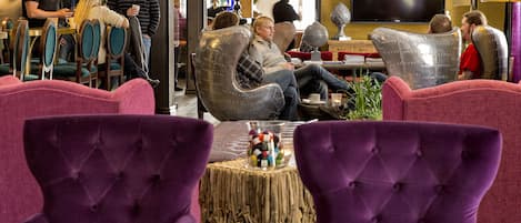 A modern lounge area with comfortable seating, a large flat-screen TV, and a casual dining setup.