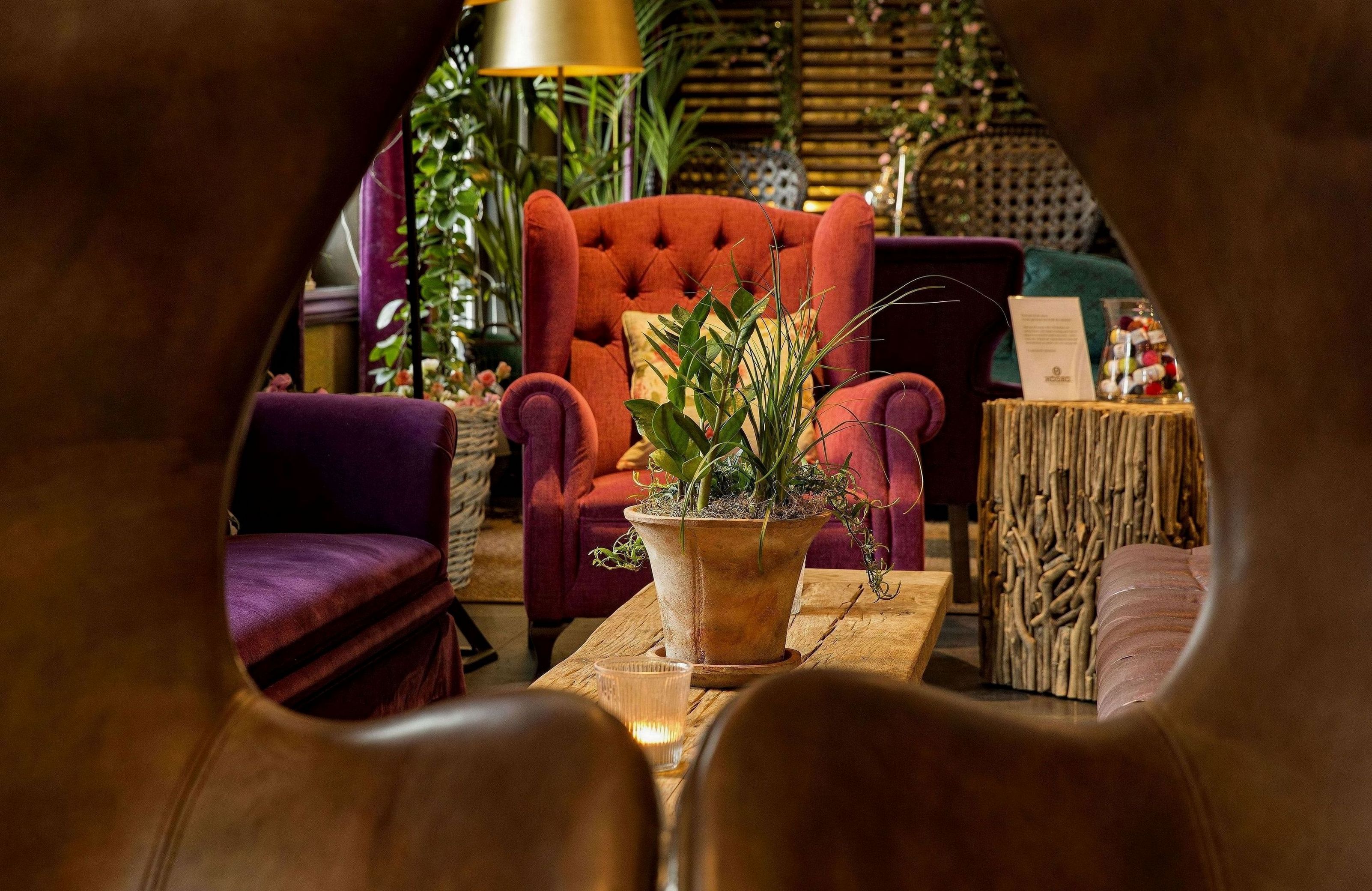 A cozy seating area with a red armchair, a wooden coffee table, and a potted plant.