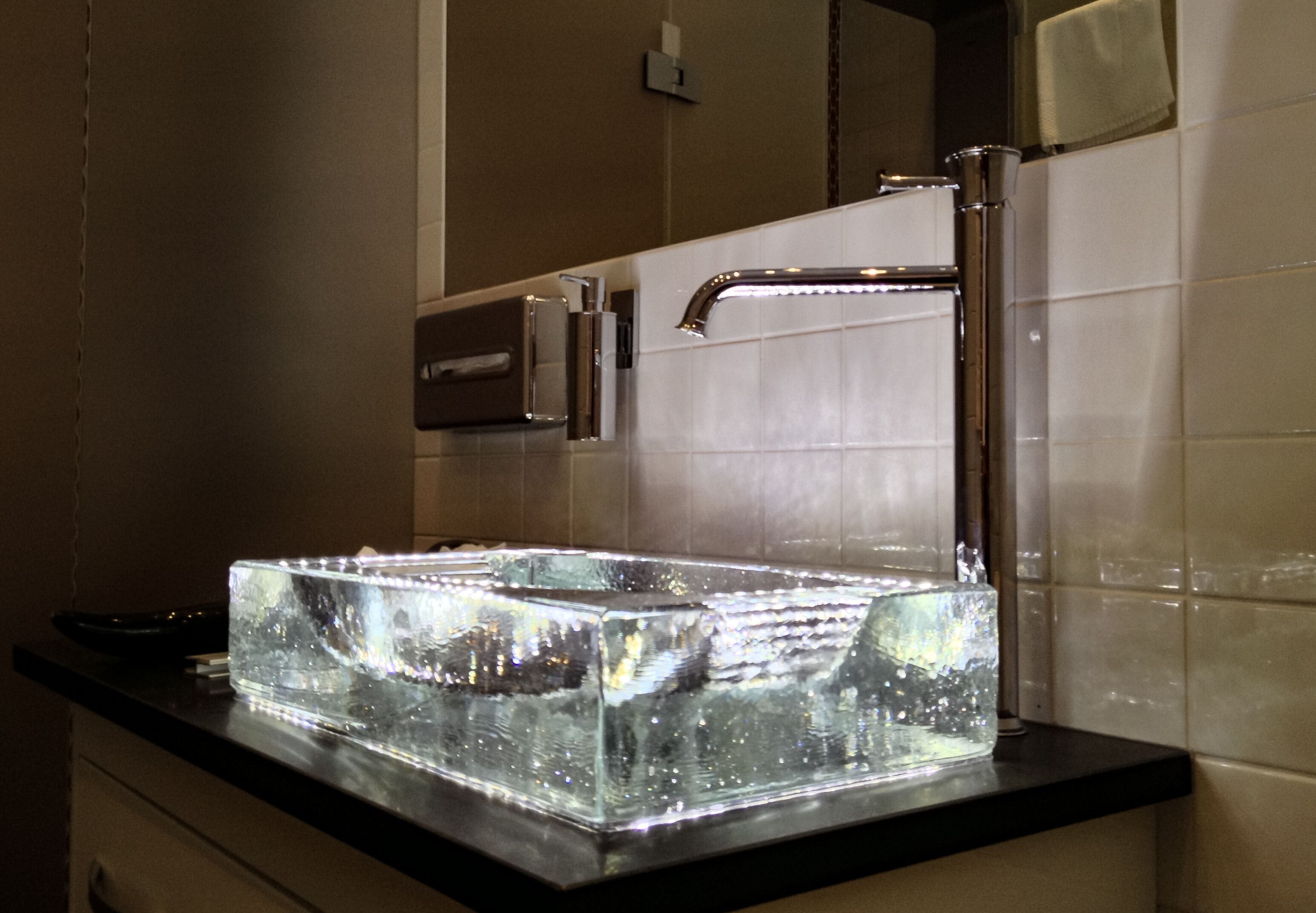 A bathroom with a modern sink, chrome faucet, and a large mirror.