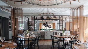 Un restaurante con barra, mesas de madera y sillas negras.