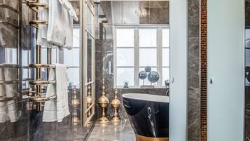 Een moderne badkamer met een groot bad, marmeren wanden en een douchecabine van glas.