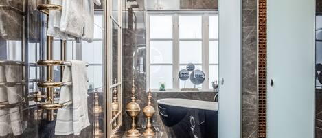 Un baño moderno con una bañera grande, paredes de mármol y cabina de ducha de vidrio.