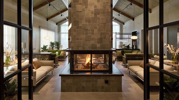 Una sala de estar moderna con chimenea de piedra, ventanas amplias y asientos cómodos.