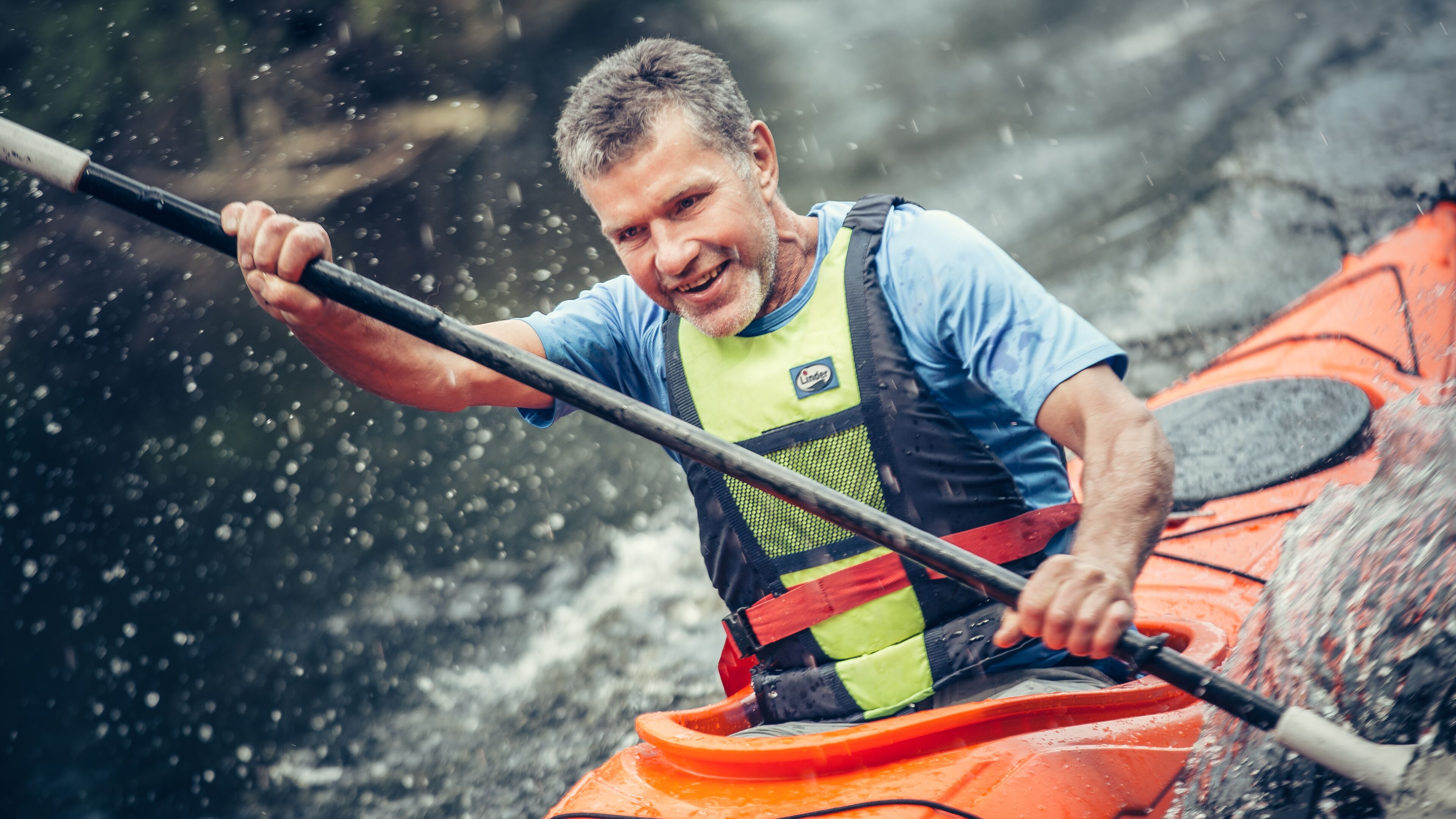 A person in a kayak wearing a life vest and holding a paddle.