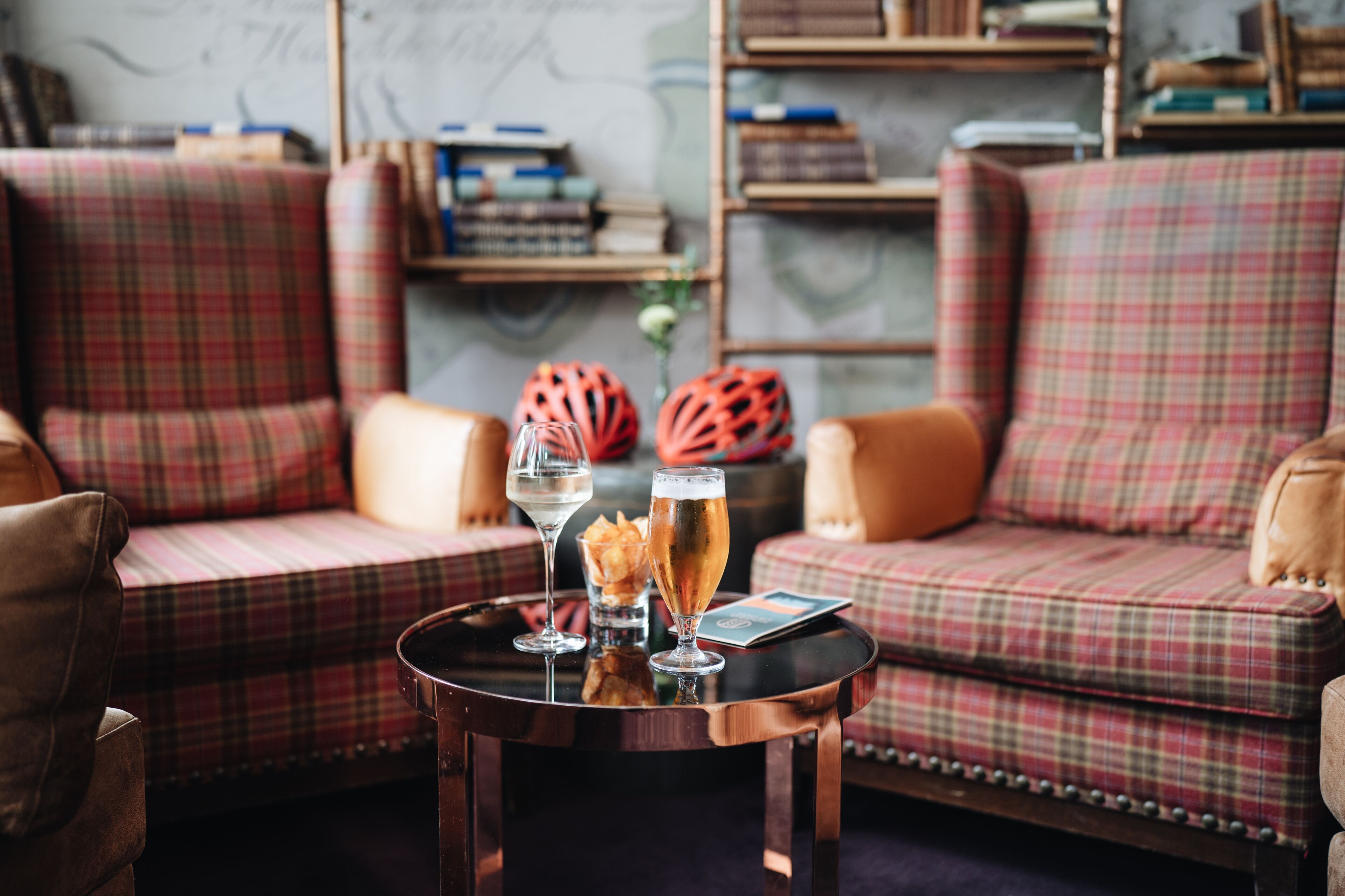 A cozy seating area with plaid sofas and a small round table with drinks and snacks.