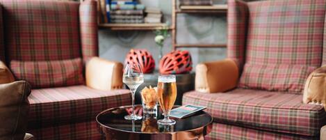 A cozy seating area with plaid sofas and a small round table with drinks and snacks.