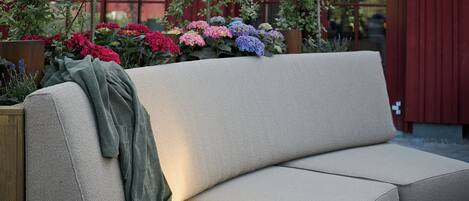 A beige sofa with a green throw blanket and sunglasses placed on it.