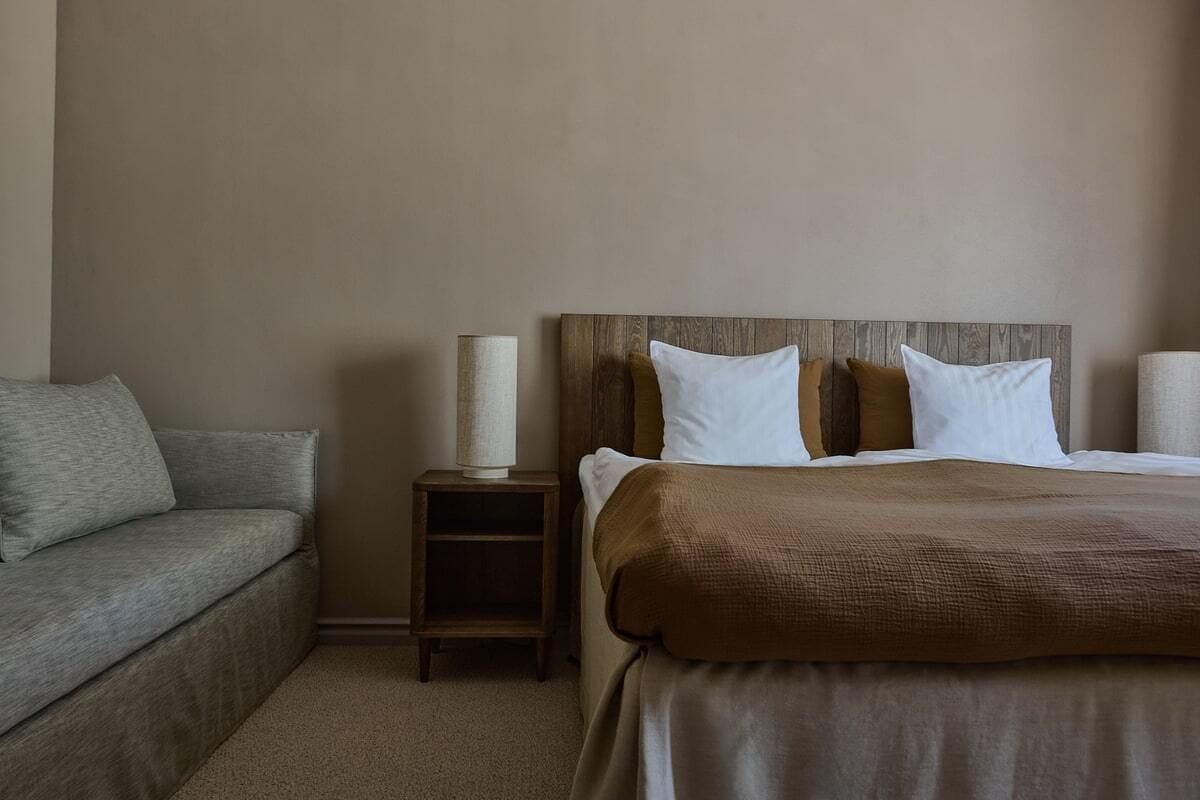 Une chambre d’hôtel avec un lit, une table de chevet, une lampe et un canapé.