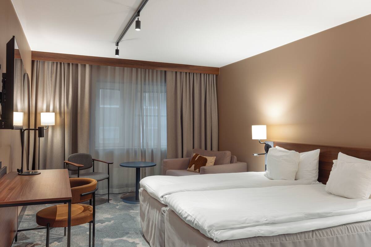 Hotellihuone, jossa on sänky, työpöytä, tuoli, pieni pöytä ja sohva.