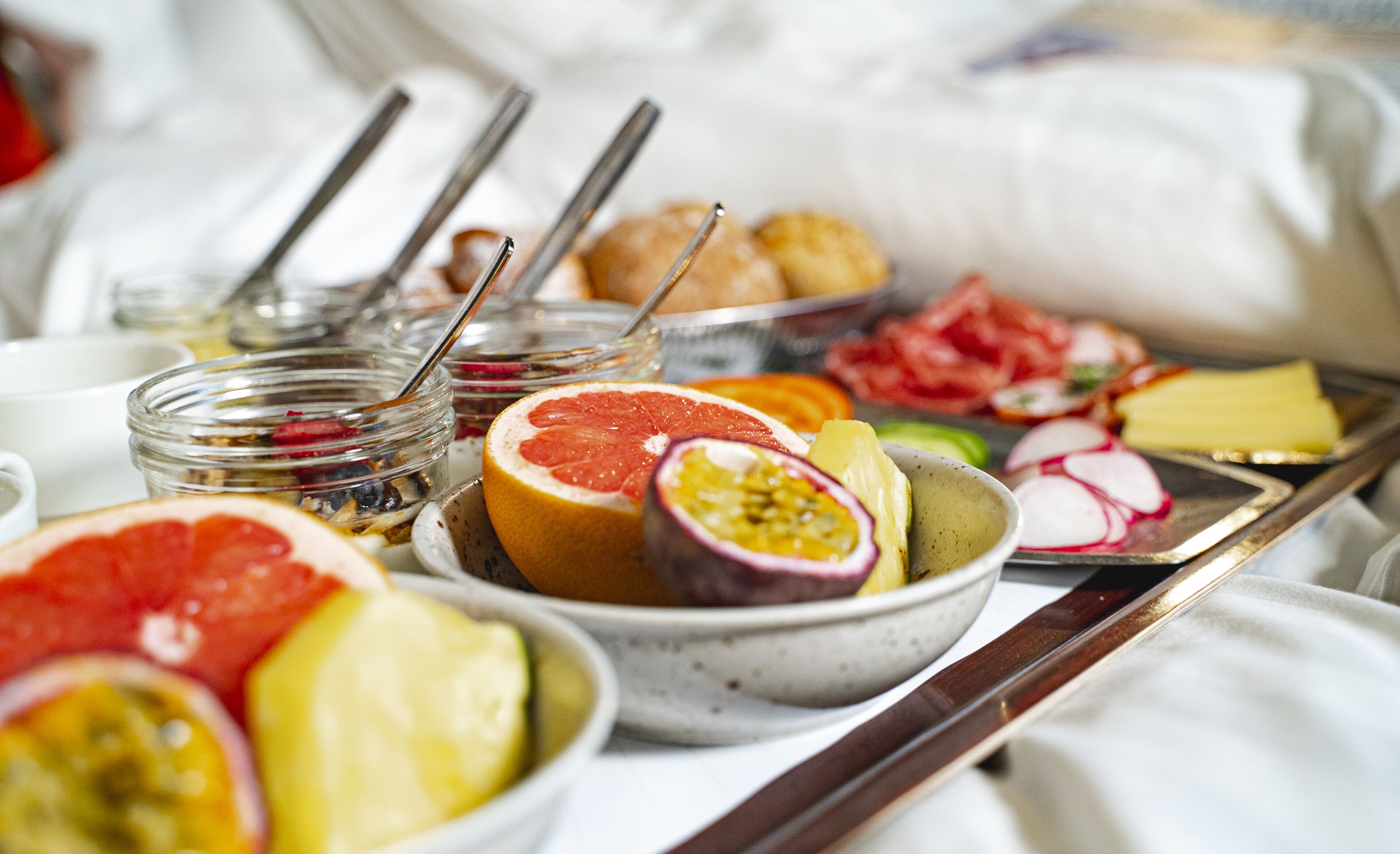 Bandeja de desayuno con frutas, pasteles y embutidos.