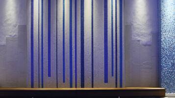 Contemporary interior design features a statement wall element with a textured, patterned surface and a lower wooden shelf.