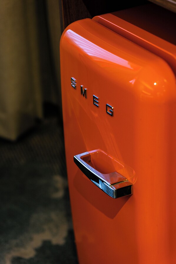 A close-up of a bright orange vintage-style luggage with the label "SMEG" on it.