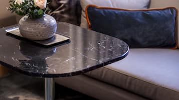 Una sala de estar moderna con una mesa redonda negra, un jarrón con flores blancas y un sofá con cojines estampados.