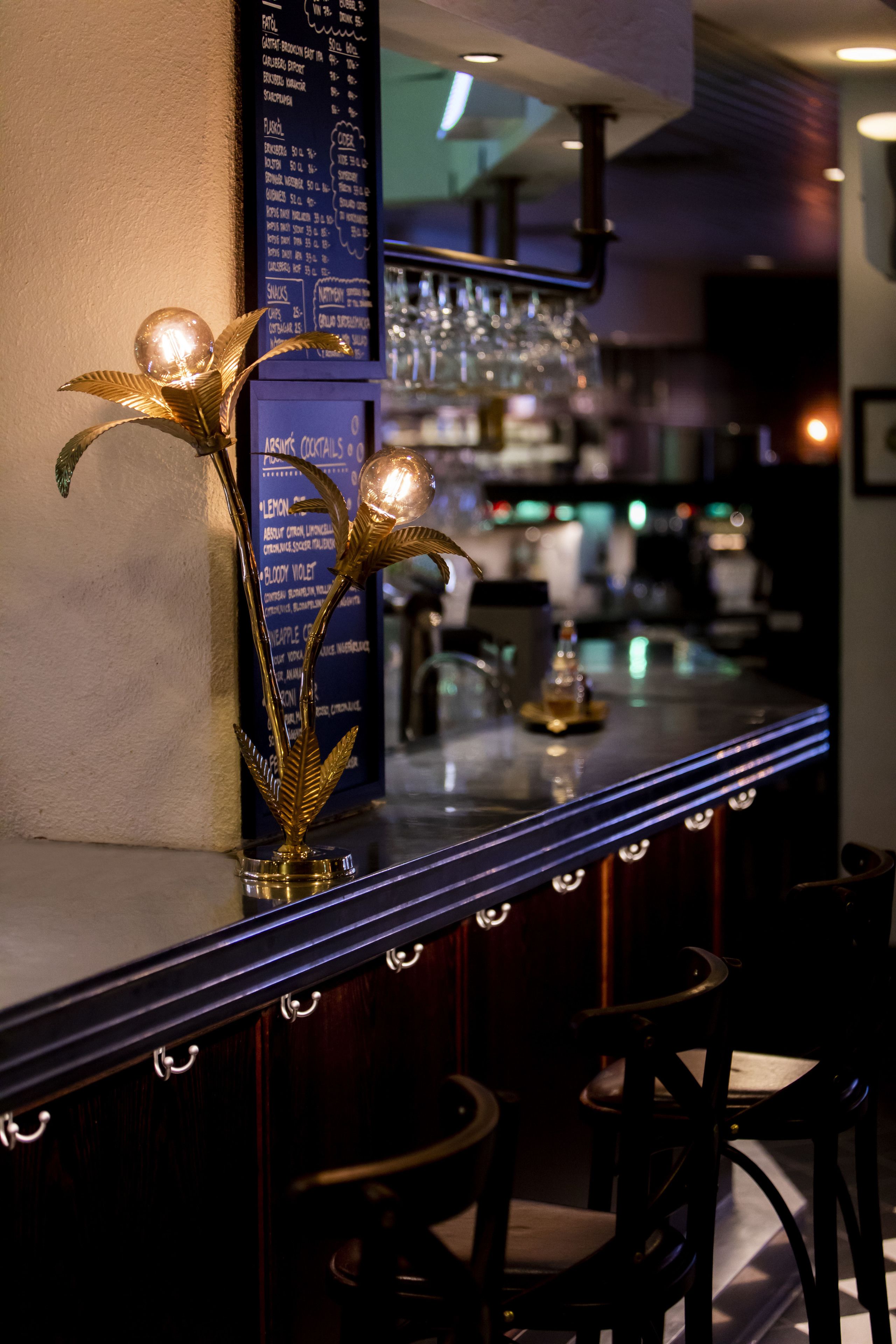 Zona de bar con una pieza central decorativa de pan de oro, un tablero de menú y taburetes.