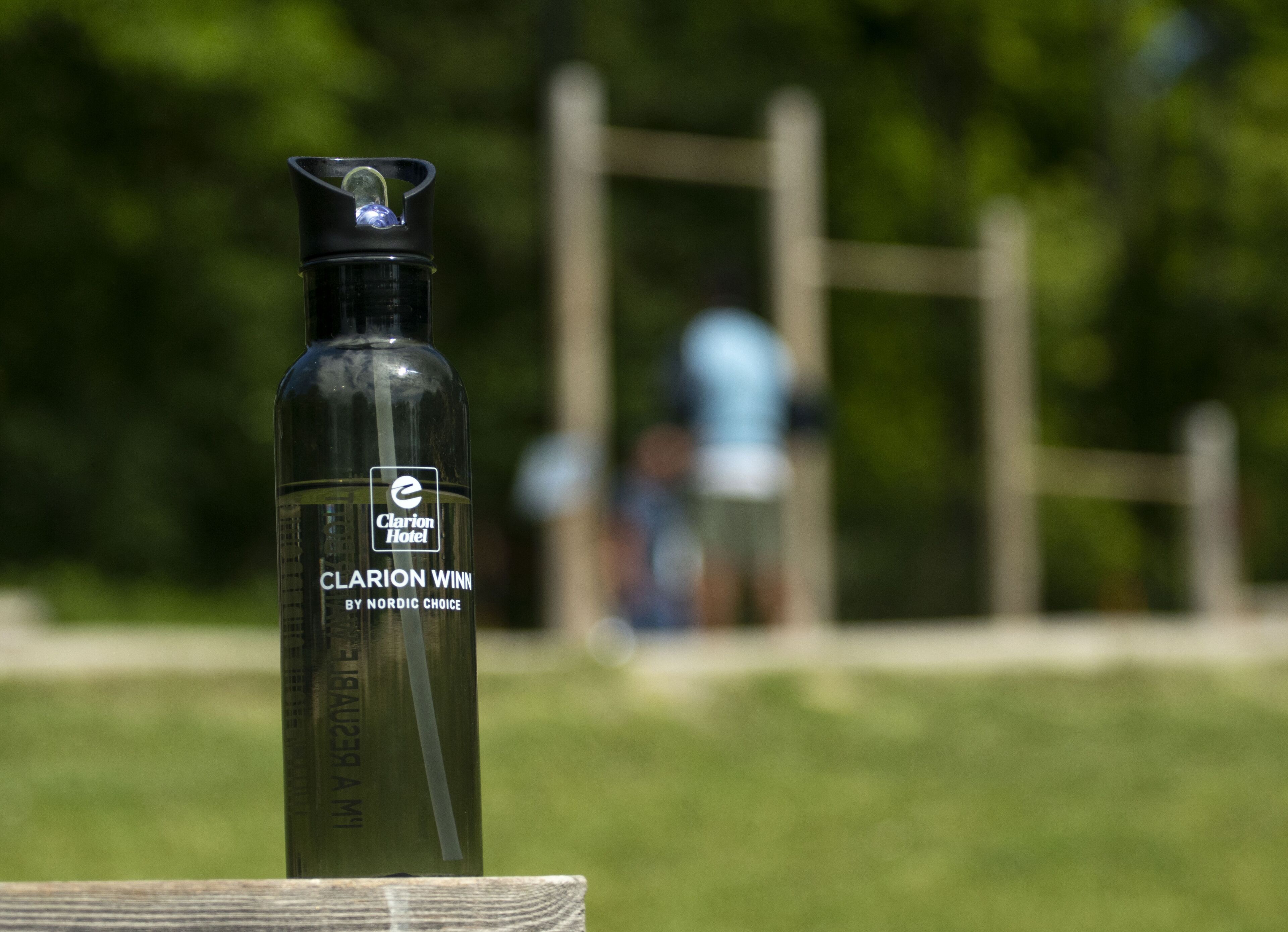 A bottle labeled 'Clarion Hotel' with a logo, placed on a wooden surface outdoors.