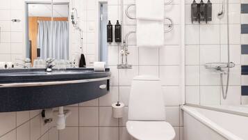 Et moderne badeværelse med toilet, vask med spejl og bruseområde.