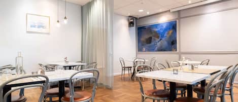 Un salón de conferencias con mesas y sillas, un cuadro abstracto grande en la pared e iluminación empotrada en el techo.