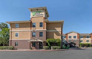 Un hotel Stay America con fachada de ladrillo, múltiples ventanas y cielo despejado.