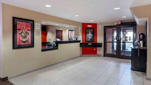 A hotel reception area with a counter, a red wall with a framed picture, and an exit sign. - Extended Stay America Suites Sacramento Elk Grove (Elk Grove)